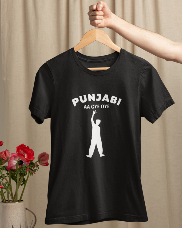 mockup-of-a-woman-s-hand-holding-a-hanger-with-a-t-shirt-over-a-table-with-flowers-m23501 (1) Punjabi Aa Gye Oye Black Unisex T-Shirt