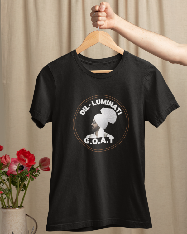 mockup-of-a-woman-s-hand-holding-a-hanger-with-a-t-shirt-over-a-table-with-flowers-m23501 (7) Dil-Luminati G.O.A.T Unisex T-Shirt